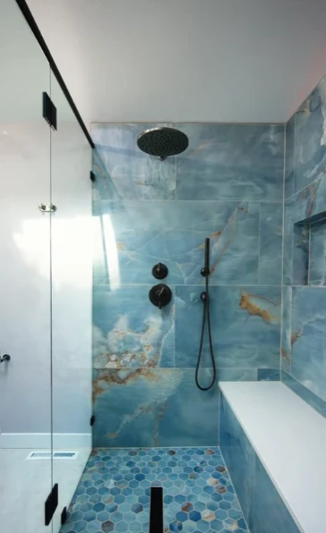 Blue marble-look shower tile with matte black fixtures and a built-in bench