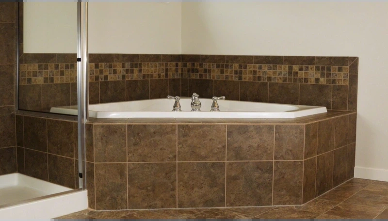 Corner tub with a brown tile deck and a mosaic accent band