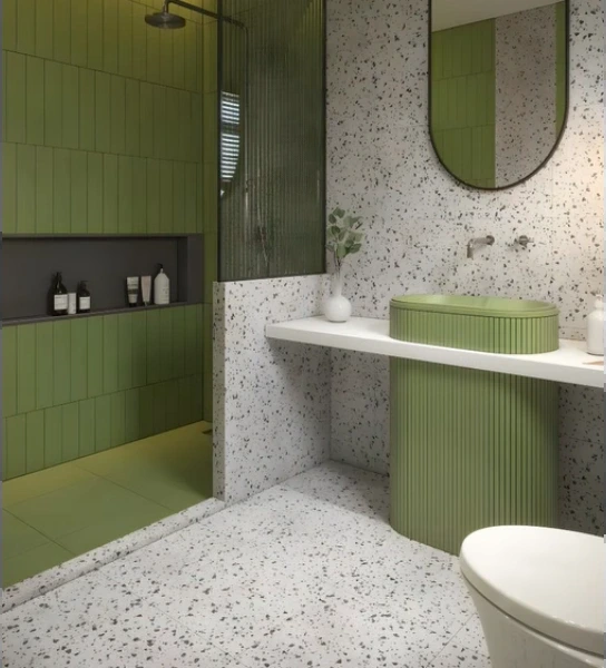 Compact bathroom with green tile shower wall, terrazzo floor and a fluted green sink