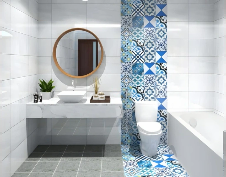 White tiled small bathroom with a blue patterned tile column and round mirror