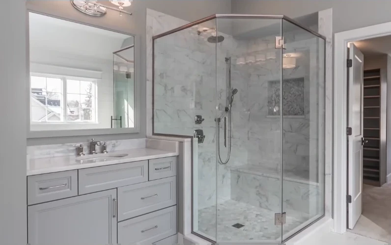 Frameless corner shower with marble-look tile and a bench next to a gray vanity