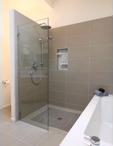 Taupe porcelain tile shower with a glass panel beside a soaking tub