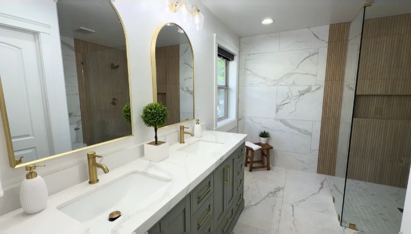 Primary bathroom with a walk-in shower, marble-look tile, green double vanity, brass faucets and arched mirrors