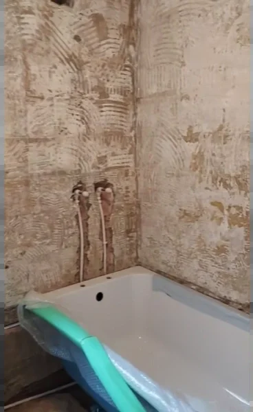 Bathroom walls stripped to bare plaster with new tub valves and a new bathtub set in place