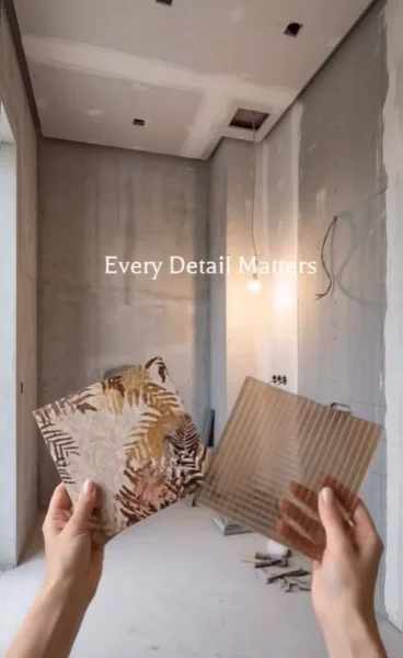 Unfinished powder room shell with concrete walls while the homeowner compares tile samples