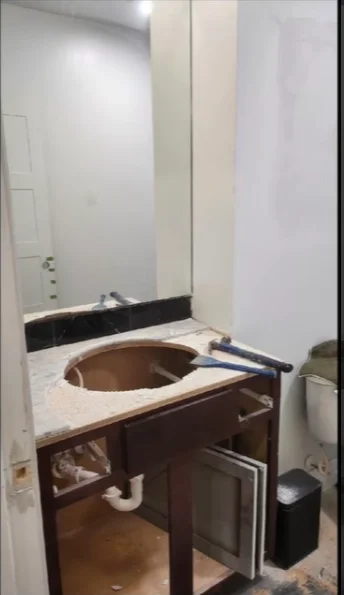 Old dark wood vanity with a copper vessel sink and a plain wall mirror