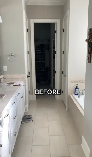 Plain bathroom with white cabinets, beige floor tile and a doorway to a closet