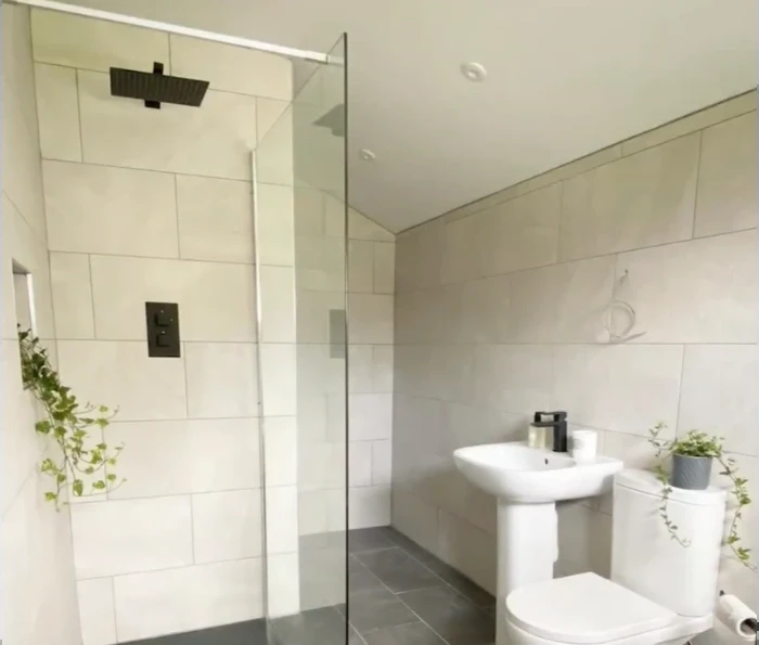 Large-format tile shower with a square black rain head and a fixed glass panel