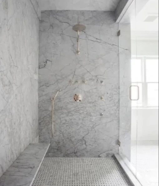 Marble-look tile walk-in shower with a corner bench and glass door