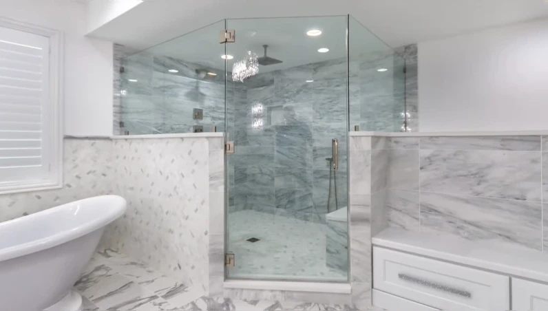 Neo-angle glass shower beside a freestanding tub in a white marble bathroom
