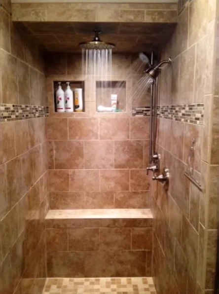Tile alcove shower with a rain head, handheld sprayer, bench and two niches