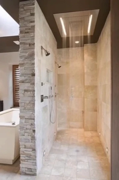 Recessed ceiling rainfall shower with a stone accent wall