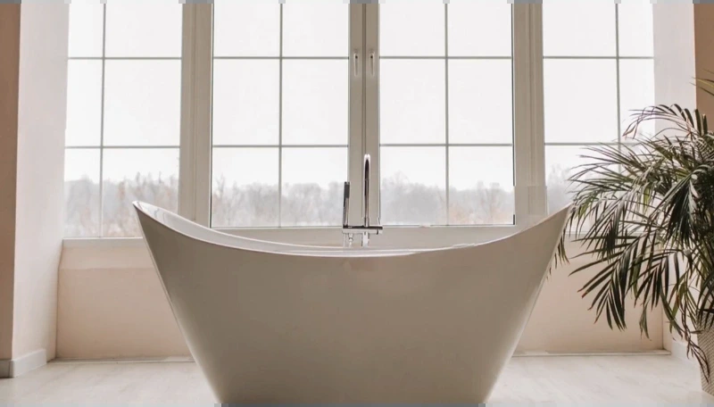 Tall slipper-style freestanding tub in front of a wide window