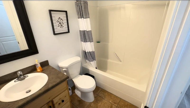 Small bathroom with a plastic tub shower combo and curtain before the remodel