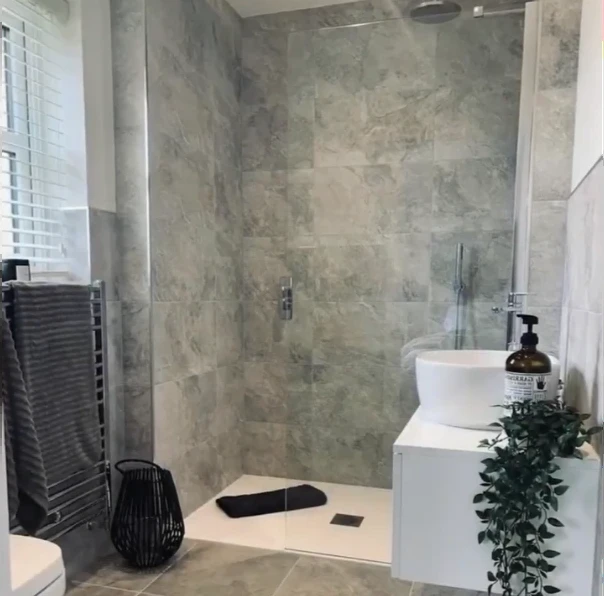 Stone-look tile shower with a low-profile tray and glass door