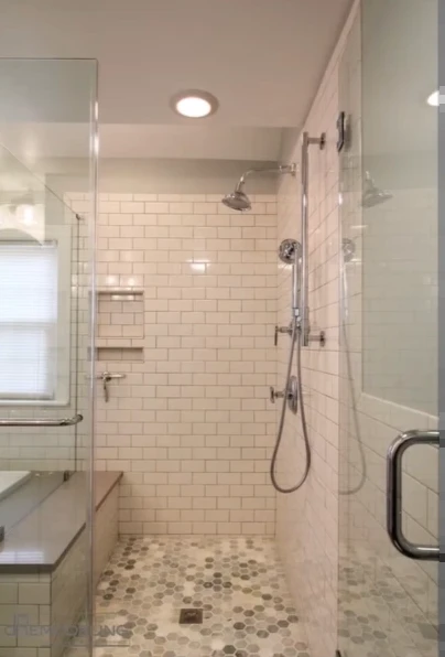 White subway tile shower with a handheld sprayer, bench and pebble floor