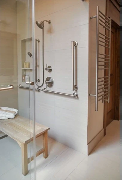 Glass-enclosed shower with a teak bench, stainless grab rails, a recessed niche and a heated towel rail
