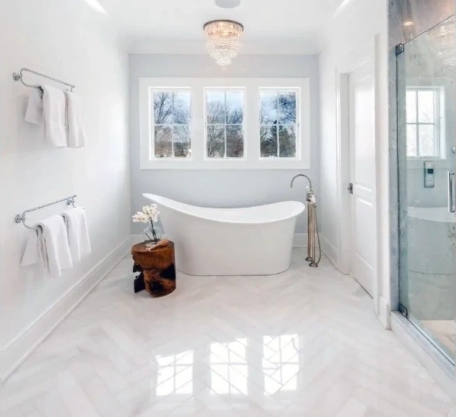 Freestanding slipper tub in a bright white bathroom with herringbone floor