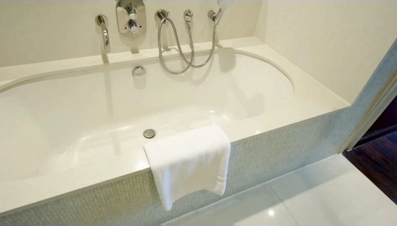 Built-in tub with a tiled deck and a handheld shower hose