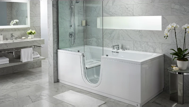 Walk-in tub with a hinged glass door and seat beside a marble-tile wall